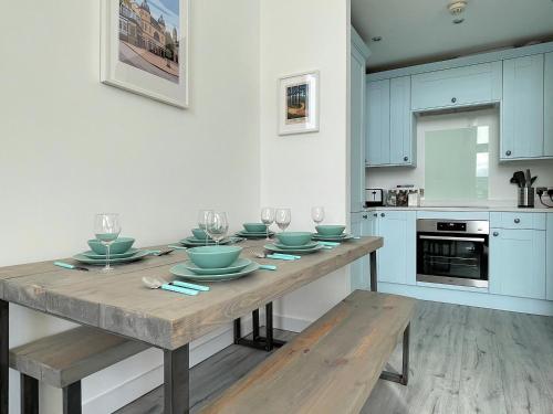 a kitchen with a wooden table with plates and wine glasses at Penthouse Apartment w/ Parking in Sheffield