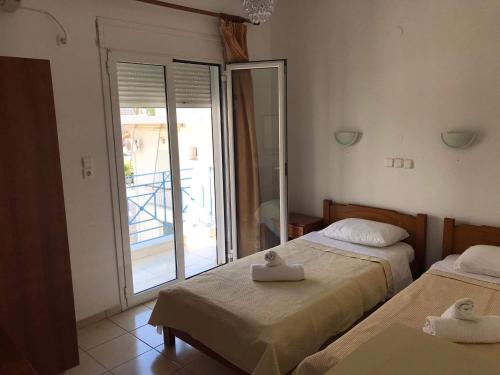 a bedroom with two beds and a door to a balcony at Αγνάντι ενοικιαζόμενα δωμάτια in Loutra Edipsou