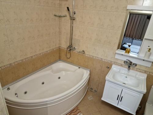 a bathroom with a white tub and a sink at Family Hotel Gotse Delchev in Gotse Delchev