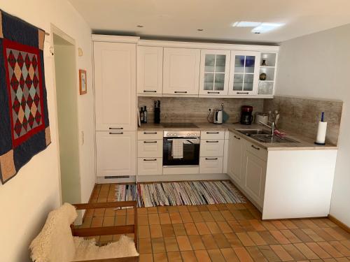 バーデン・バーデンにあるFerienwohnung am Krippenhofの白いキャビネットとコンロ付きオーブンを備えたキッチン