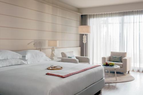 a white bedroom with a large white bed and chairs at Lefay Resort & Spa Lago Di Garda in Gargnano