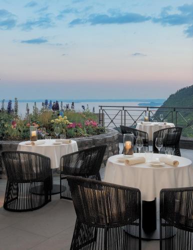 a restaurant with tables and chairs with the ocean in the background at Lefay Resort & Spa Lago Di Garda in Gargnano