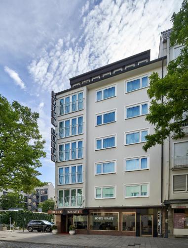 a tall white building with a car parked in front of it at Hotel Kraft in Munich