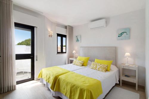 a bedroom with a bed with yellow sheets and a window at Casa Harlequin in Vale do Lobo