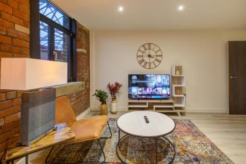 a living room with a tv and a brick wall at Stylish 'New York Loft' 2 Bed Apartment in Bradford