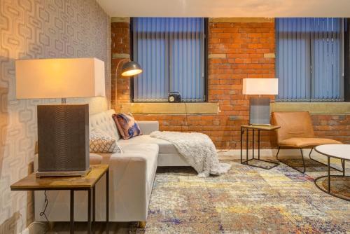 a living room with a white couch and a brick wall at Stylish 'New York Loft' 2 Bed Apartment in Bradford