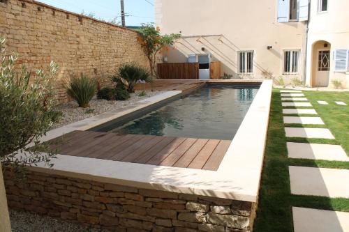 a swimming pool with a wooden deck and a brick wall at Clos Ceres in Viré