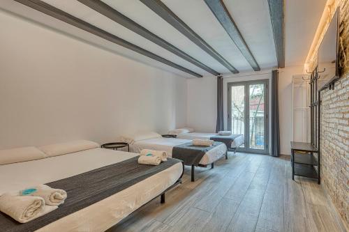 a bedroom with two beds and a brick wall at HOSTAL BEDMATES in Barcelona