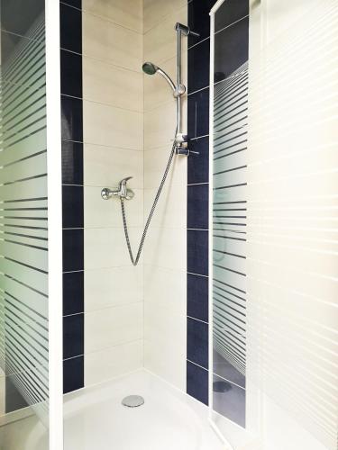 y baño con ducha y azulejos blancos y negros. en noclegi KALMA en Ostróda