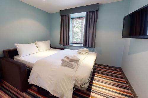 a hotel room with two beds and a flat screen tv at Village Hotel Manchester Hyde in Hyde