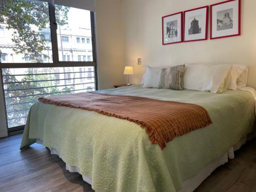 a bedroom with a large bed with a large window at Barrio Lastarria, Excelentes Apartamentos - Sofia Camilla Propiedades in Santiago