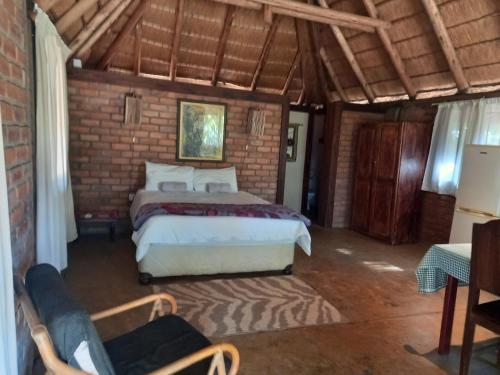 1 dormitorio con cama y pared de ladrillo en Shankara Rest Camp, en Makena