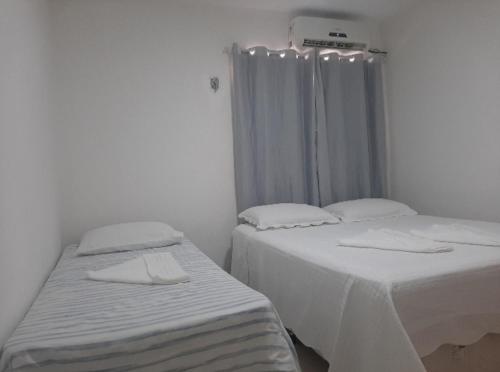 two twin beds in a white room with a window at FlatStudio01 em condomínio residencial na Nova Betânia in Mossoró
