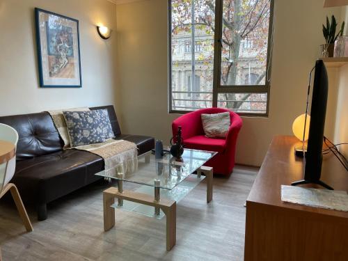 sala de estar con sofá negro y silla roja en Barrio Lastarria, Excelentes Apartamentos - Sofia Camilla Propiedades, en Santiago