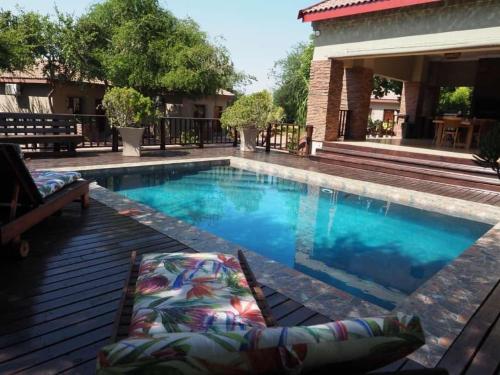 a swimming pool with a chaise lounge next to a house at African Dream Tour in Hoedspruit