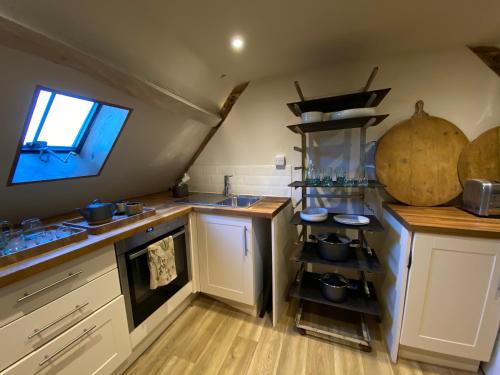 a kitchen with white cabinets and a sink and a window at The Hayloft in Stonehouse