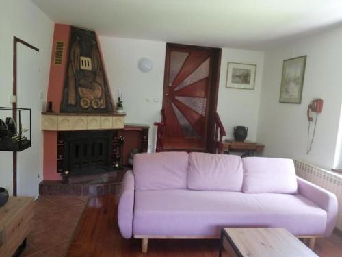 een paarse bank in een woonkamer met een open haard bij Holiday Home Jakovci in Netretić