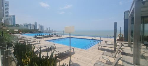 een zwembad met stoelen en de oceaan op de achtergrond bij H2 Hyatt Vista Mar in Cartagena