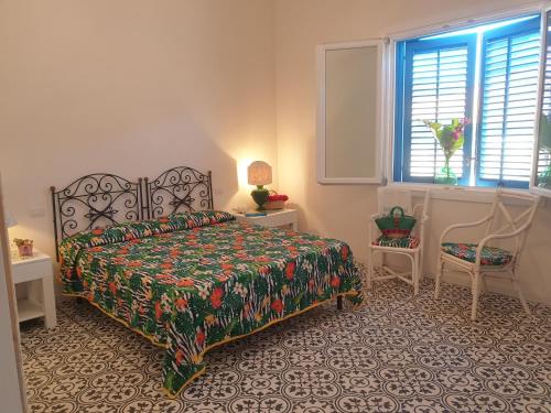 um quarto com uma cama, uma cadeira e uma janela em Dimora Quattro Vanelle em Favignana