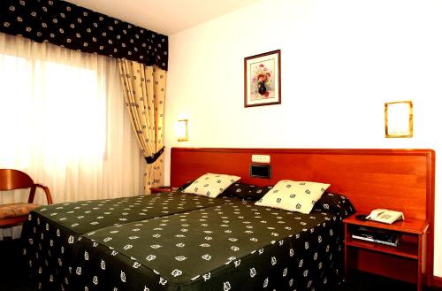 a bedroom with a bed with a black and white bedspread at Hotel Scala in Padrón