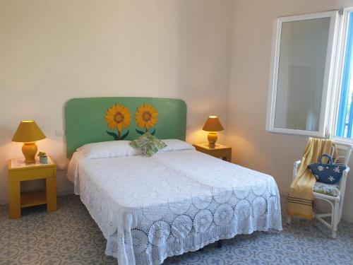 una camera da letto con un letto con testiera verde e fiori sopra di Dimora Quattro Vanelle a Favignana