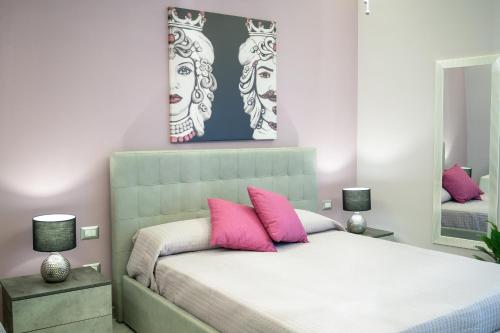 a bedroom with a bed with two pink pillows at Tyche apartaments & rooms in Taormina