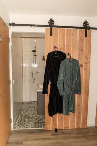 a bathroom with a sliding door with a robe at Veldschuur Nijverdal in Nijverdal