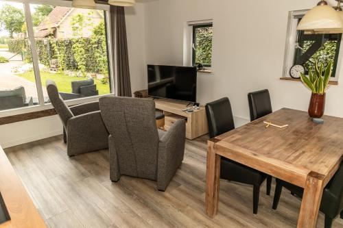 a living room with a table and chairs and a television at Veldschuur Nijverdal in Nijverdal