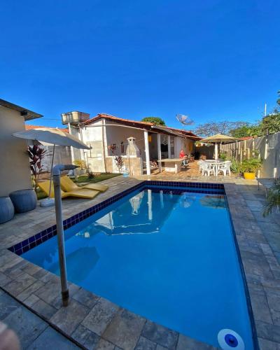 a swimming pool with an umbrella and a house at CASA ALUNAI in Pirenópolis