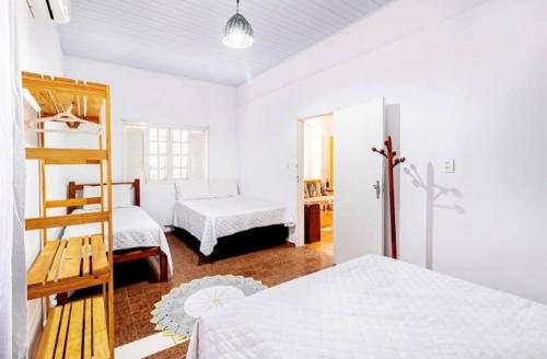 a white bedroom with two beds and a ladder at CASA ALUNAI in Pirenópolis