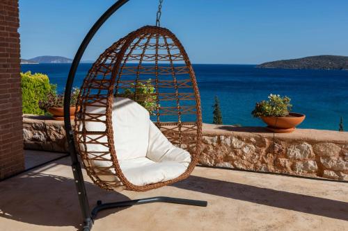 a swinging chair on a patio with a view of the ocean at Gold Sun Villas in Nafplio