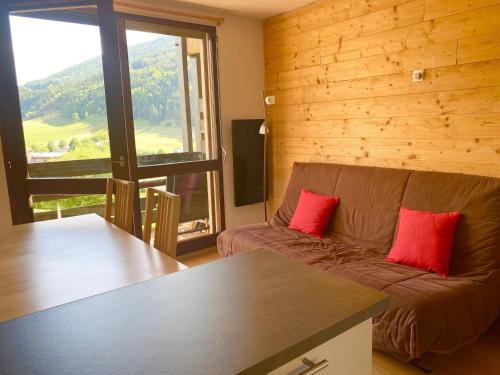 - un salon avec un canapé et 2 oreillers rouges dans l'établissement Duplex 6 pers avec balcon plein sud à Villard-de-Lans, proche village et navettes gratuites - FR-1-515-130, à Villard-de-Lans