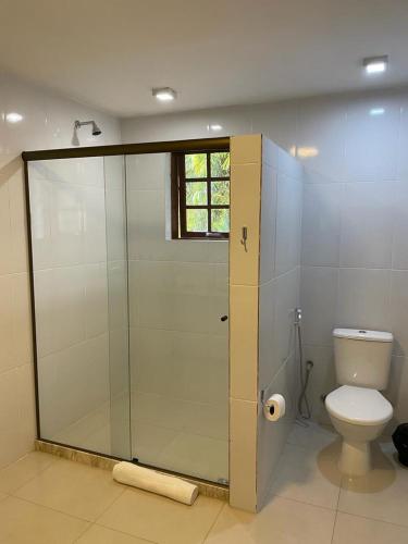 a bathroom with a shower with a toilet and a window at Pousada Cozy House in Itaipava