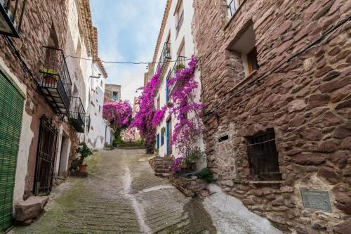 an alley in an old town with purple flowers at Casa Montesa in Vilafames