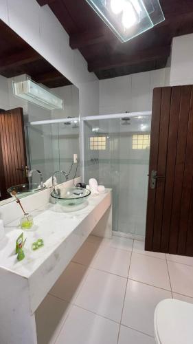 a bathroom with a sink and a glass shower at Pousada Cozy House in Itaipava