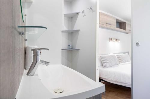 a bathroom with a tub and a bed in a room at Càmping Vila Village in Sant Feliu de Buixalleu