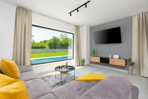 a living room with a couch and a large window at Modern 300m2 Villa - King Beds & Leisure Zone in Tinjan