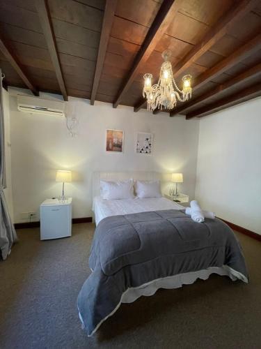 a bedroom with a large bed and a chandelier at Pousada Cozy House in Itaipava