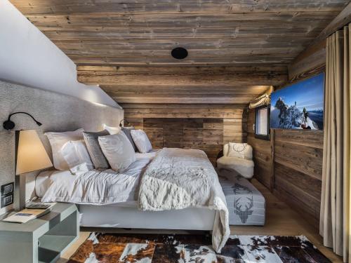 una camera da letto con un letto e una parete di legno di Chalet de luxe avec jacuzzi, salle cinéma et piscine au centre de Megève - FR-1-569-10 a Megève