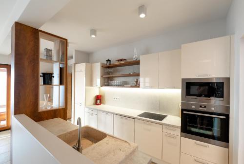 a kitchen with white cabinets and a stove top oven at Seafront Stone Villa in Blato