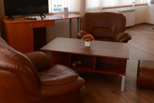 a living room with a coffee table and a chair and a television at Family Hotel Gotse Delchev in Gotse Delchev