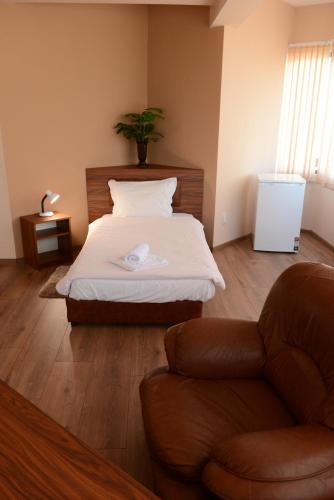 a bedroom with a bed and a chair and a couch at Family Hotel Gotse Delchev in Gotse Delchev