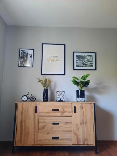 a wooden dresser in a room with three pictures on the wall at Meerhuuske Käthe in Südbrookmerland