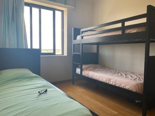 サン・マルティーニョ・ド・ポルトにあるBeachfront 3bdr apt on Marginal Boulevardのベッドルーム1室(二段ベッド2台、窓付)が備わります。