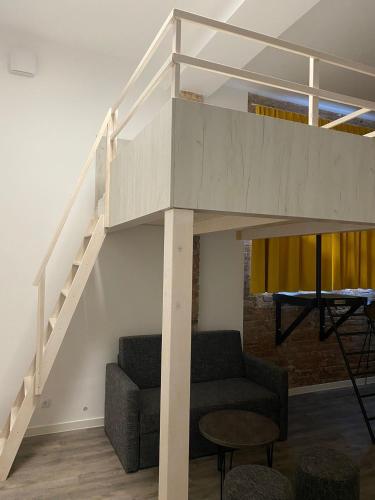 a loft bed with a staircase in a living room at Stuck Ferienwohnungen in Cottbus