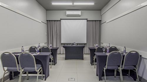 a conference room with tables and chairs and a screen at Hotel Deville Express Cascavel in Cascavel