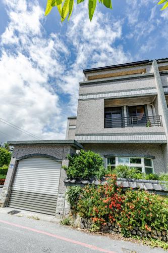 a house with a garage door and some flowers at Hualien Wazuka Homestay in Hualien City