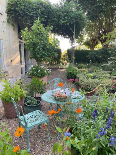 un jardin avec une table, des chaises et des fleurs dans l'établissement Les Jardins Haute Couture, à Huismes