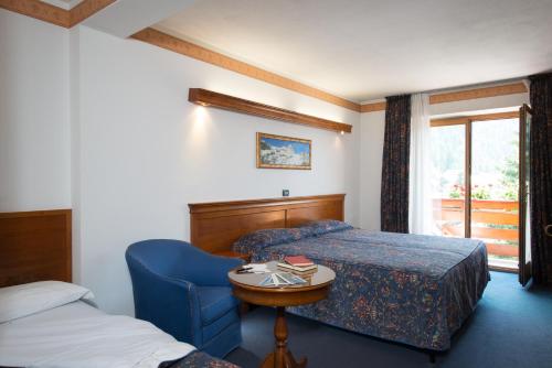 a bedroom with a bed and a table and a chair at Hotel Tourist in Valtournenche