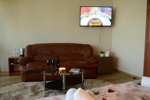 a living room with a brown leather couch and a tv at Family Hotel Gotse Delchev in Gotse Delchev